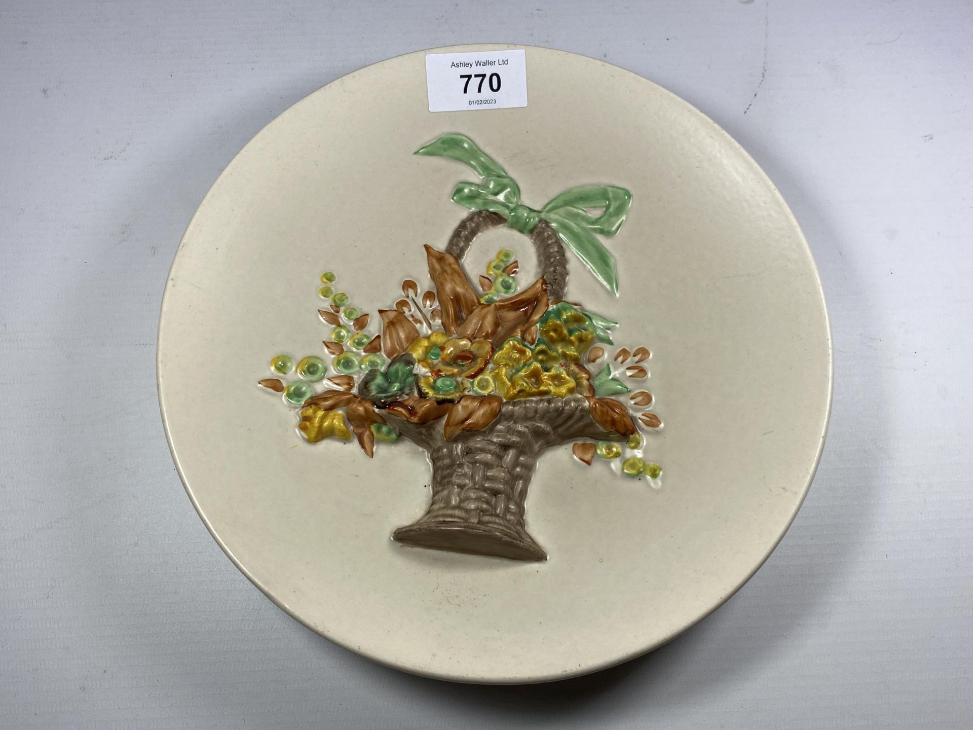 A CLARICE CLIFF POTTERY PLATE WITH BASKET OF FLOWER RELIEF MOULDED DESIGN