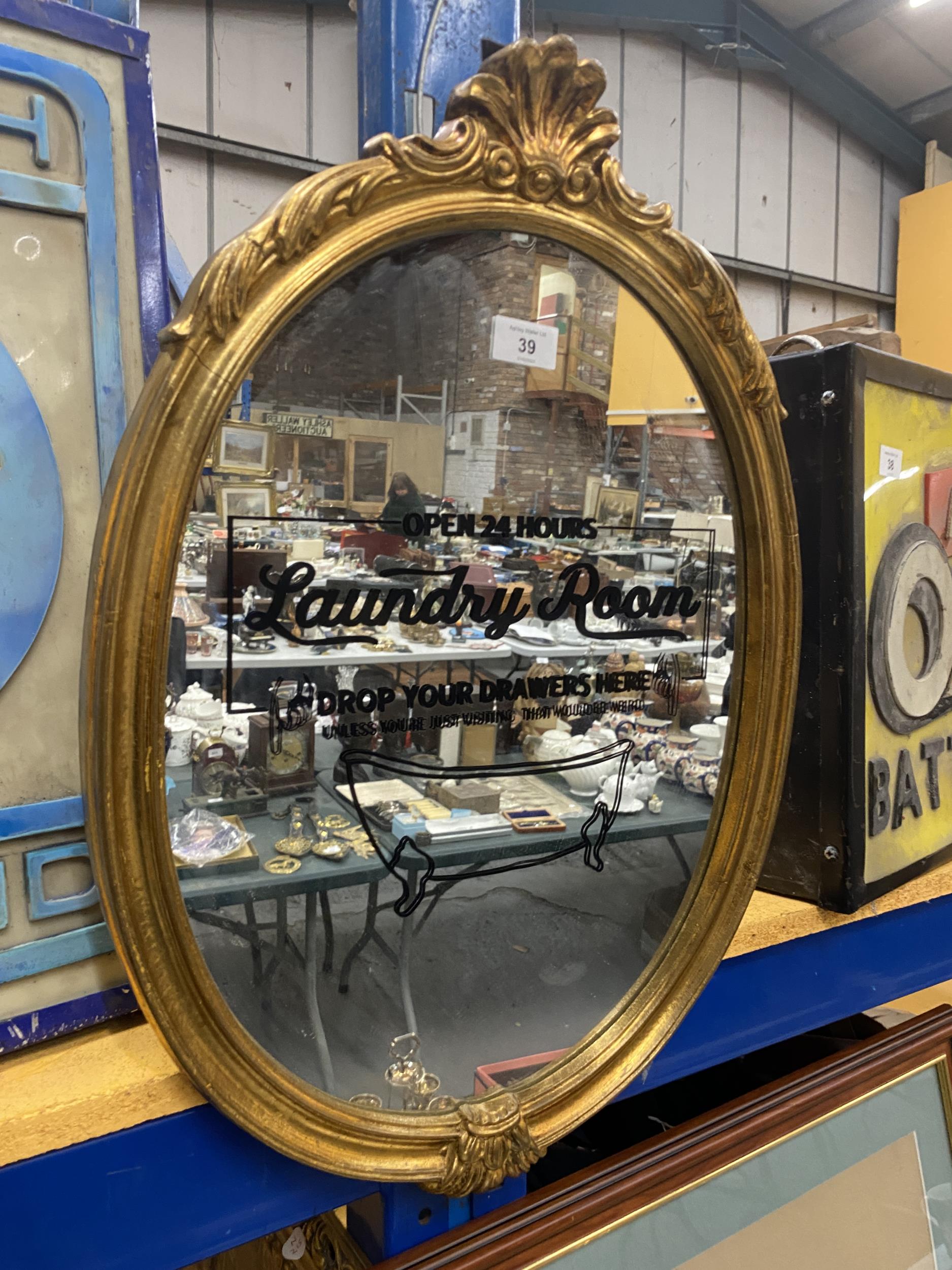 AN OVAL GILT FRAMED 'LAUNDRY ROOM' DROP YOUR DRAWERS HERE MIRROR, HEIGHT 60CM