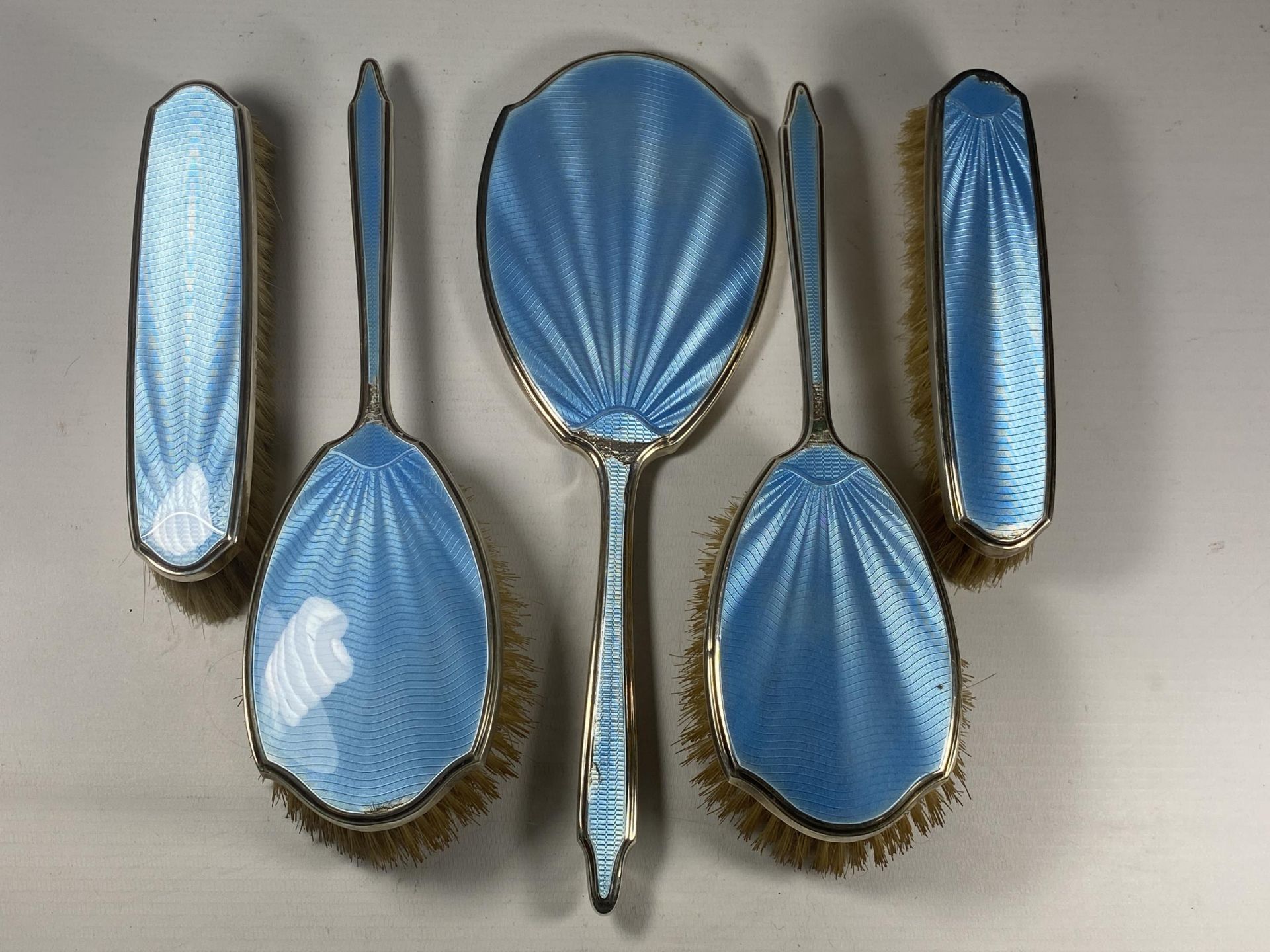 A FIVE PIECE HALLMARKED SILVER BACKED & BLUE GUILLOCHE ENAMEL DRESSING SET COMPRISING TWO HAIR