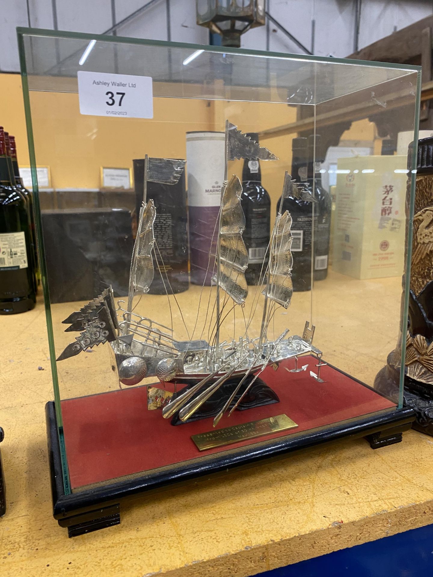 A PRESENTATION SILVER EFFECT WHITE METAL MODEL OF A BOAT IN A GLASS DISPLAY CASE