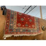 A RED PATTERNED FRINGED RUG