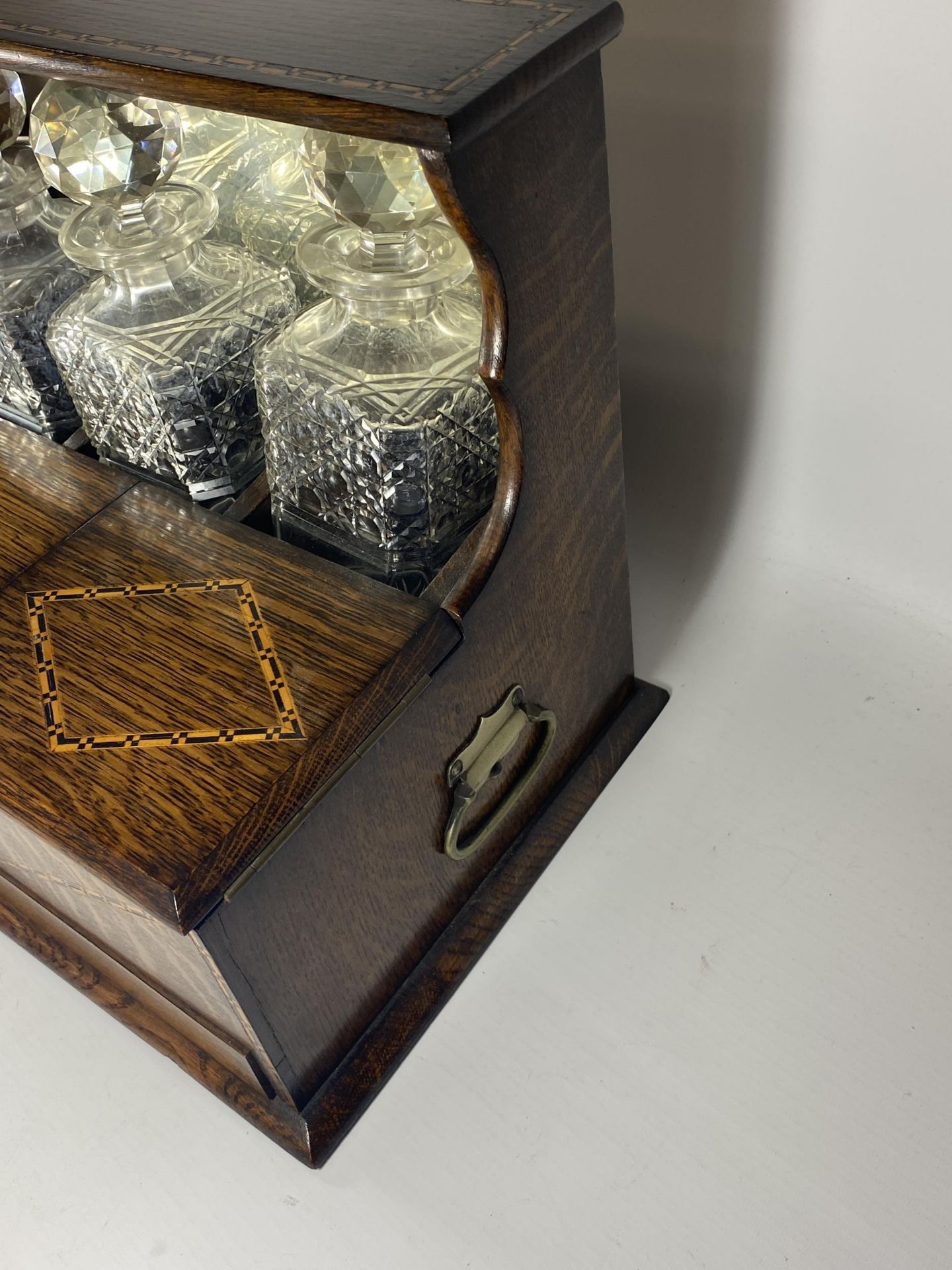 AN EDWARDIAN INLAID OAK THREE BOTTLE TANTALUS HOLDER WITH TWIN LIDDED COMPARTMENT AND LOWER DRAWER - Image 5 of 6