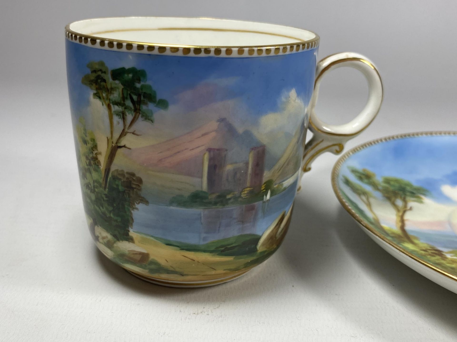 A 19TH CENTURY HAND PAINTED PORCELAIN CUP AND SAUCER WITH LAKE & CASTLE SCENE, CROSS/WING MARK TO - Image 3 of 5