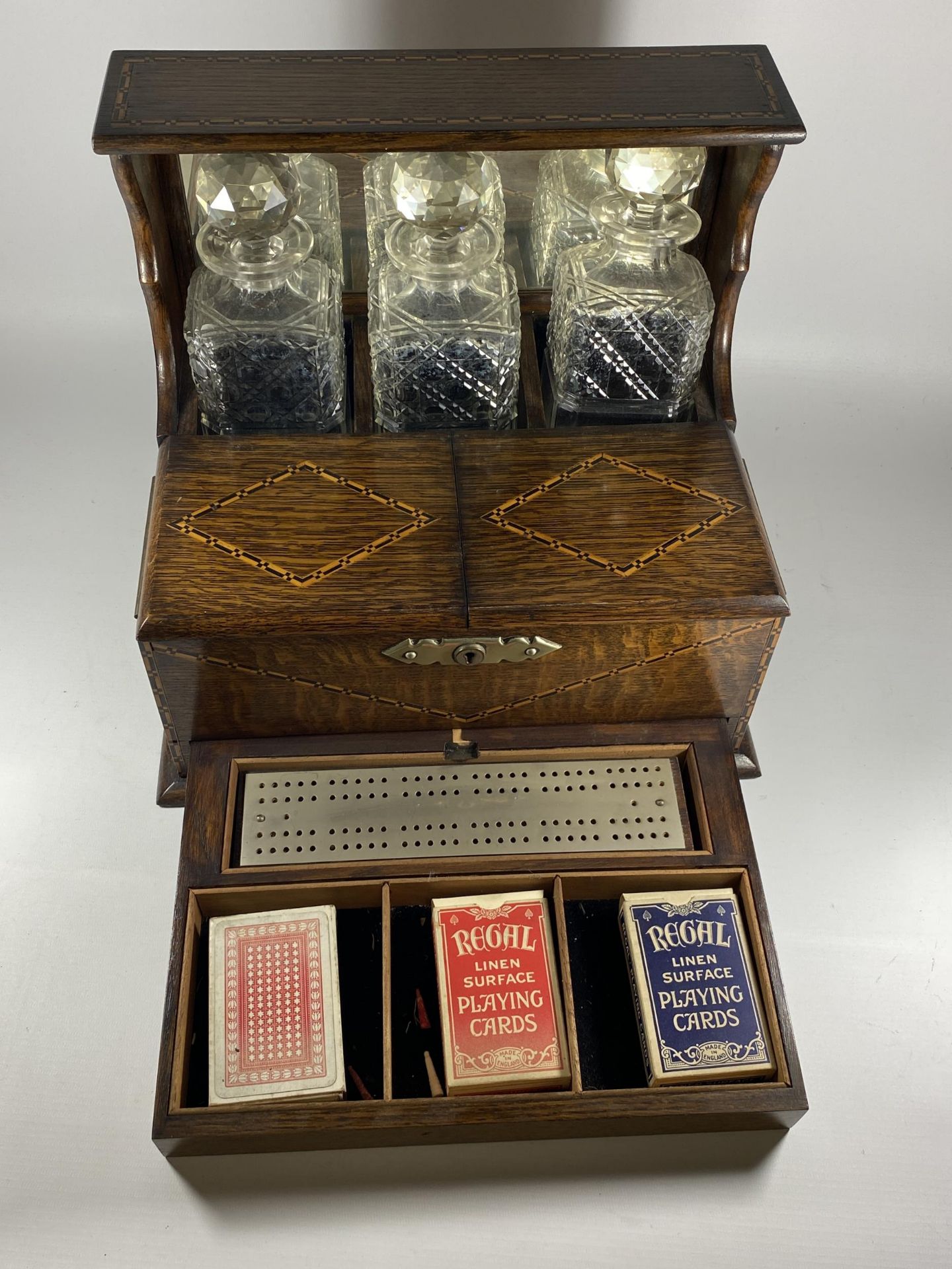 AN EDWARDIAN INLAID OAK THREE BOTTLE TANTALUS HOLDER WITH TWIN LIDDED COMPARTMENT AND LOWER DRAWER - Image 4 of 6