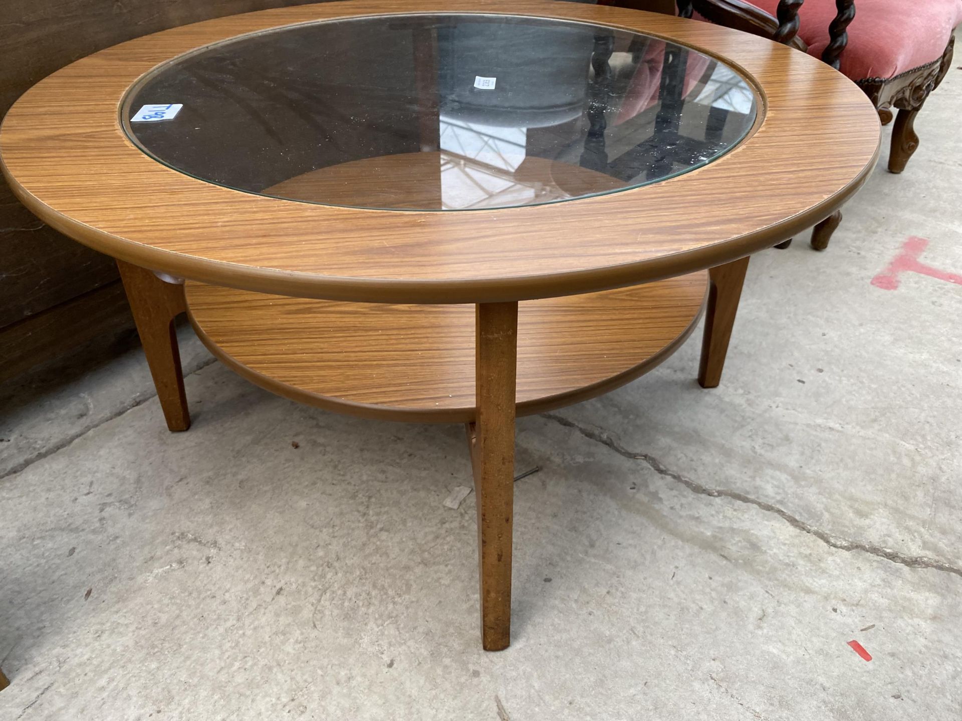 A RETRO TEAK 33" DIAMETER TWO TIER COFFEE TABLE WITH INSET GLASS TOP