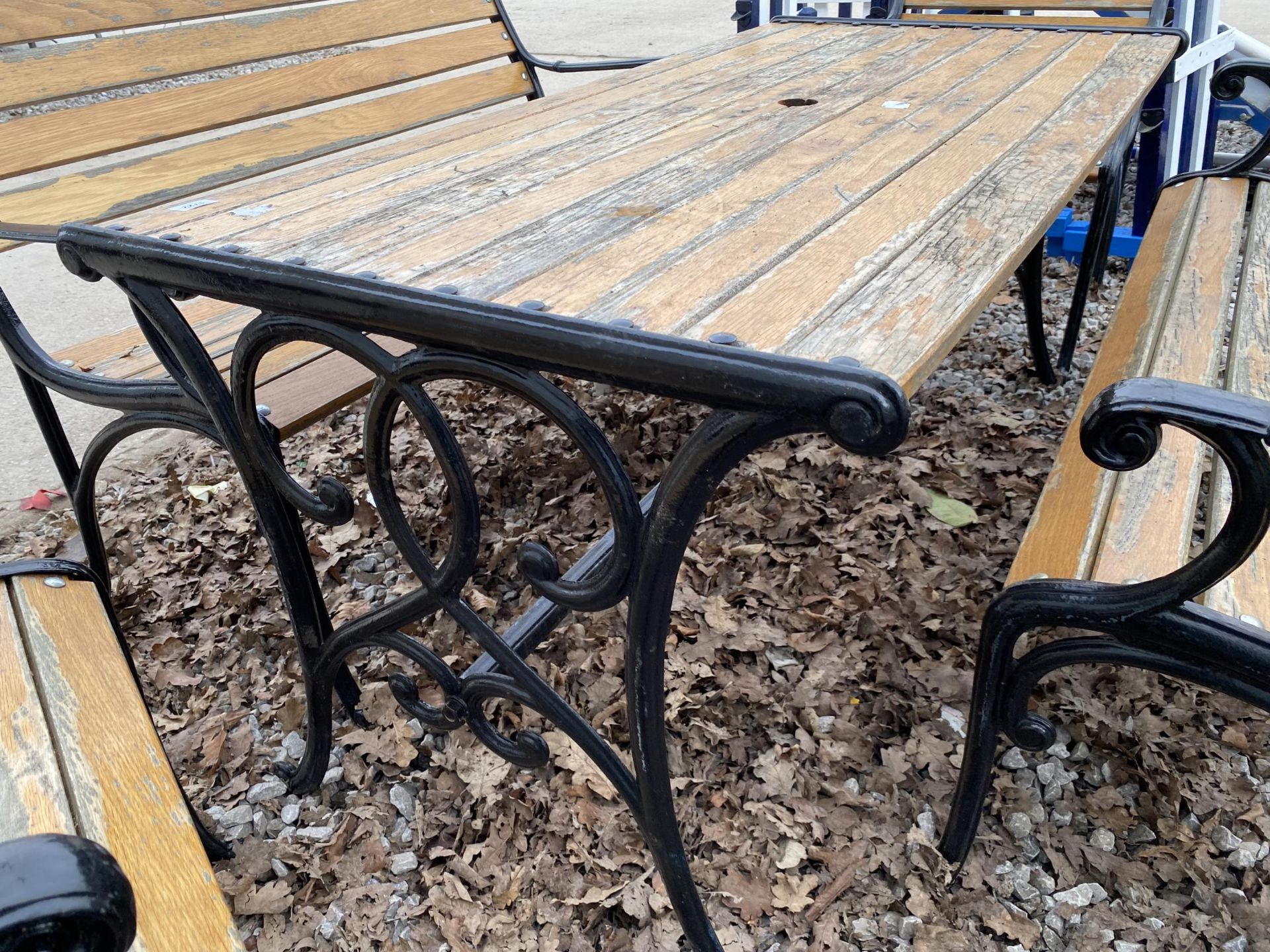 A WOODEN SLATTED PATIO FURNITURE SET WITH CAST TABLE BASE, TWO BENCHES AND TWO CHAIRS WITH CAST ENDS - Image 5 of 7