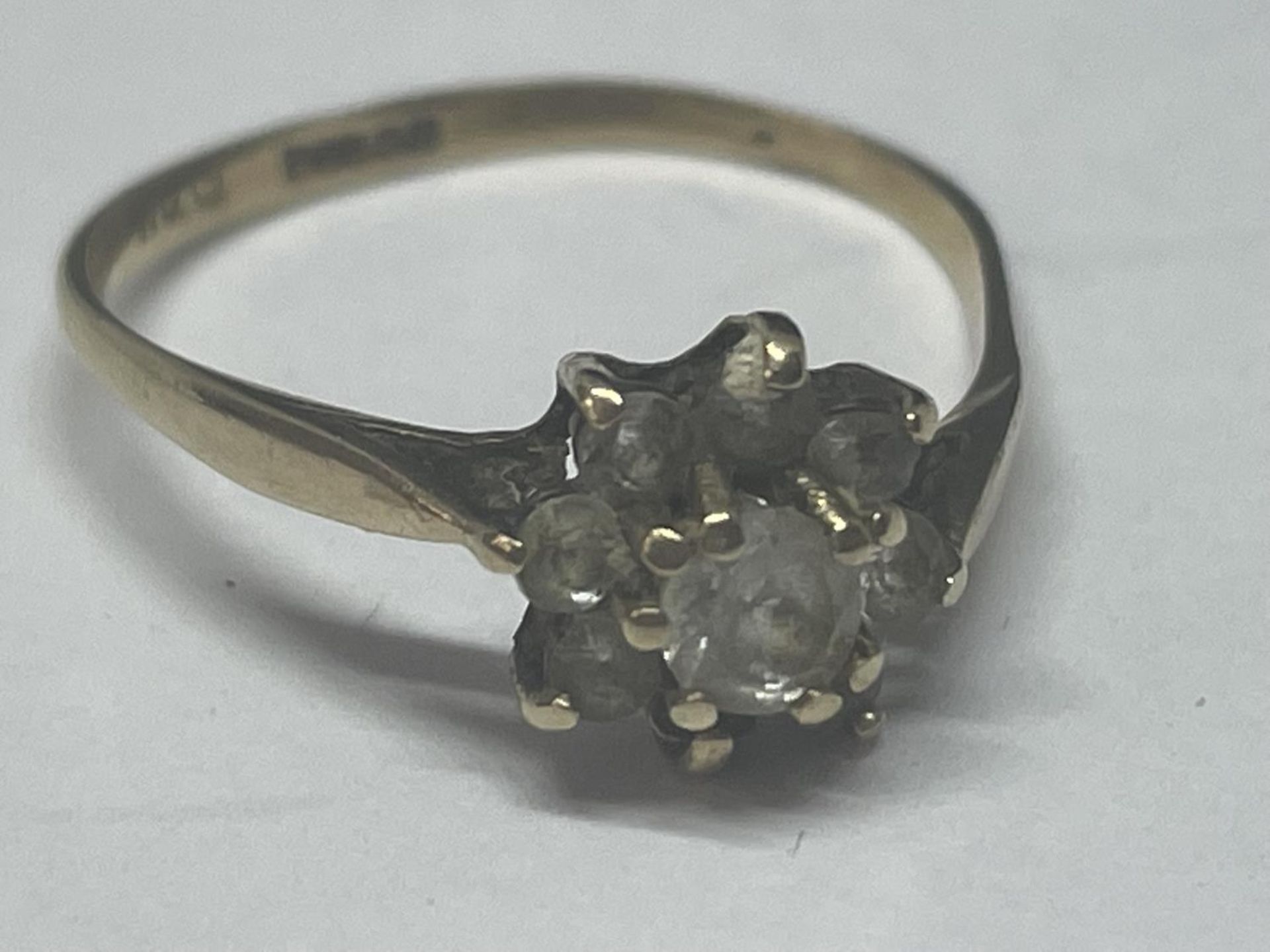 A 9 CARAT GOLD RING WITH CLEAR STONES IN A FLOWER DESIGN SIZE M/N GROSS WEIGHT 1.24 GRAMS