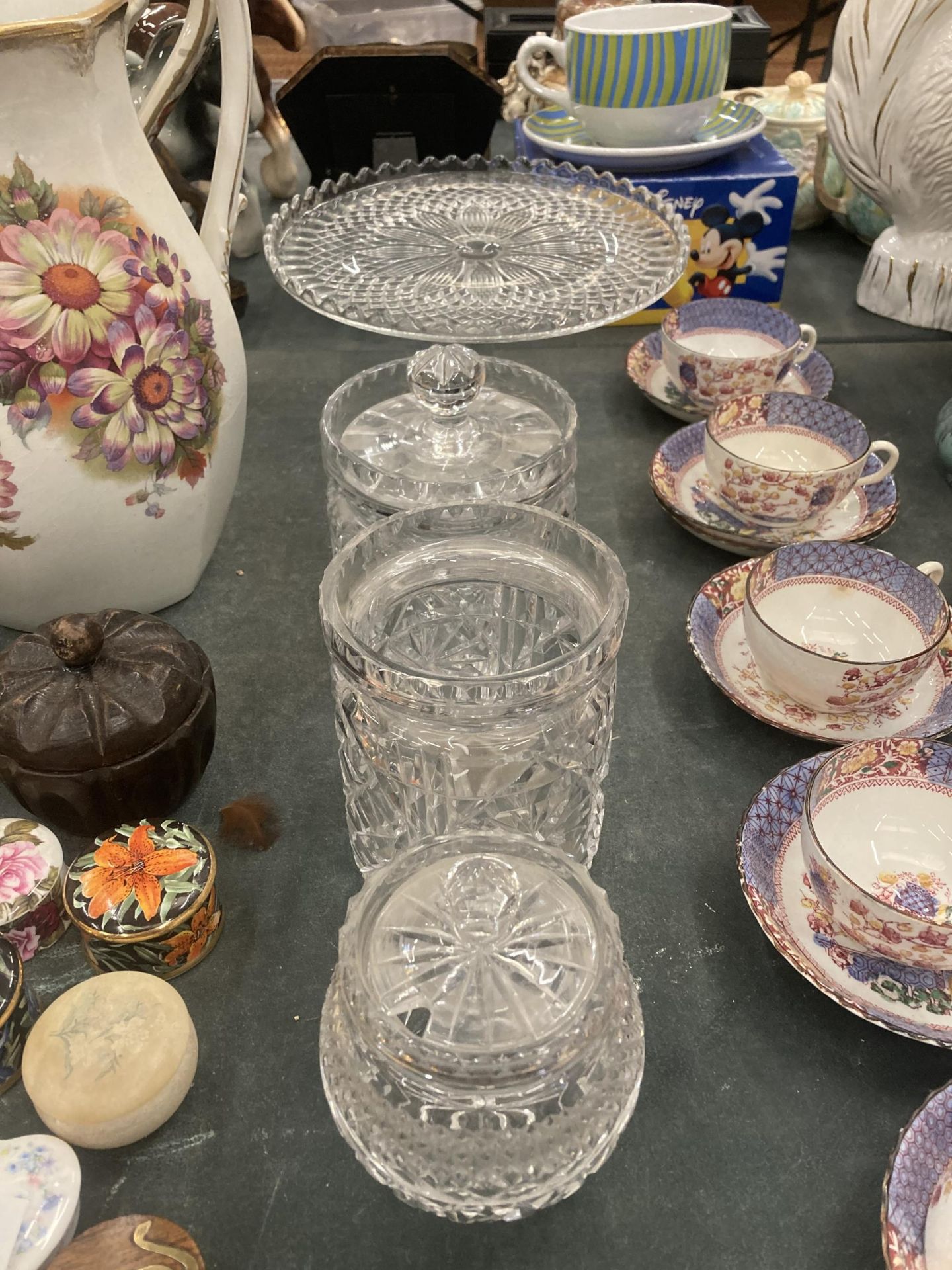 A GLASS FOOTED CAKE STAND, PLUS THREE STORAGE JARS