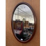 AN OVAL MAHOGANY FRAMED BEVELED EDGE WALL MIRROR