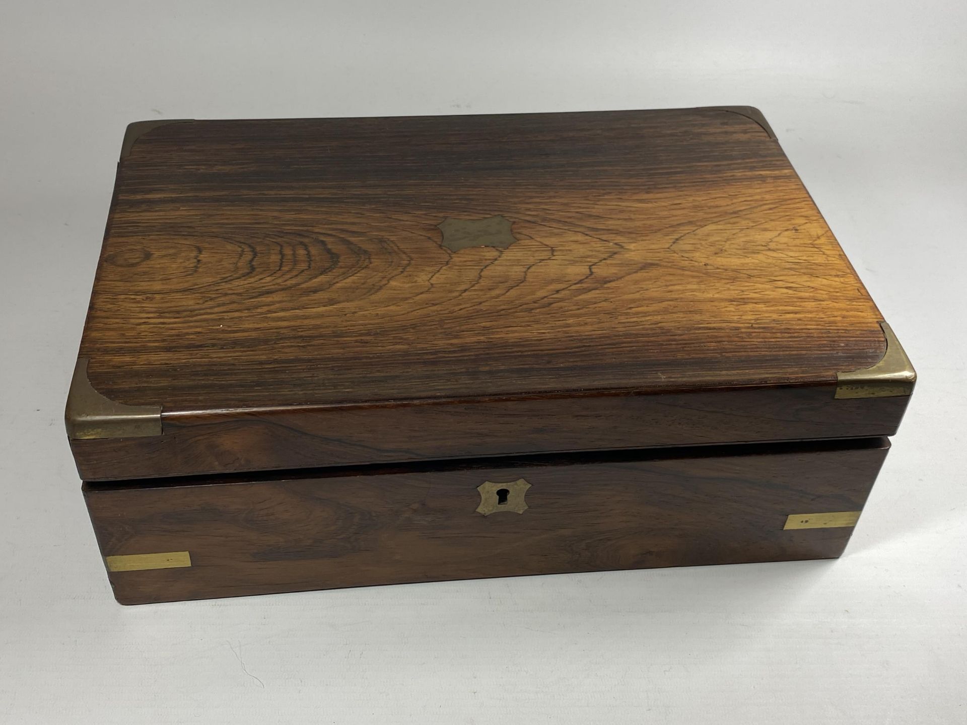 A VINTAGE MAHOGANY AND BRASS BOUND WRITING SLOPE WITH TWO BRASS TOPPED INKWELLS AND INNER VELVET