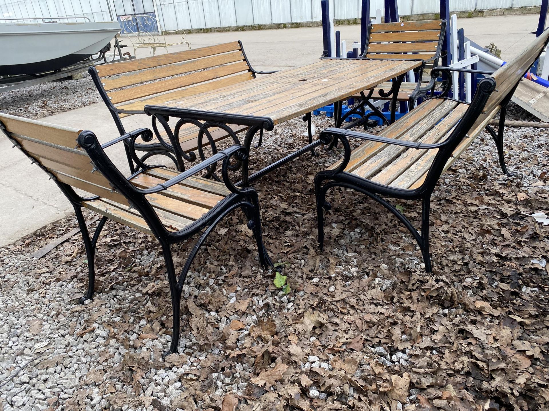 A WOODEN SLATTED PATIO FURNITURE SET WITH CAST TABLE BASE, TWO BENCHES AND TWO CHAIRS WITH CAST ENDS - Image 2 of 7