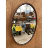 AN OVAL WOODEN FRAMED BEVELED EDGE WALL MIRROR
