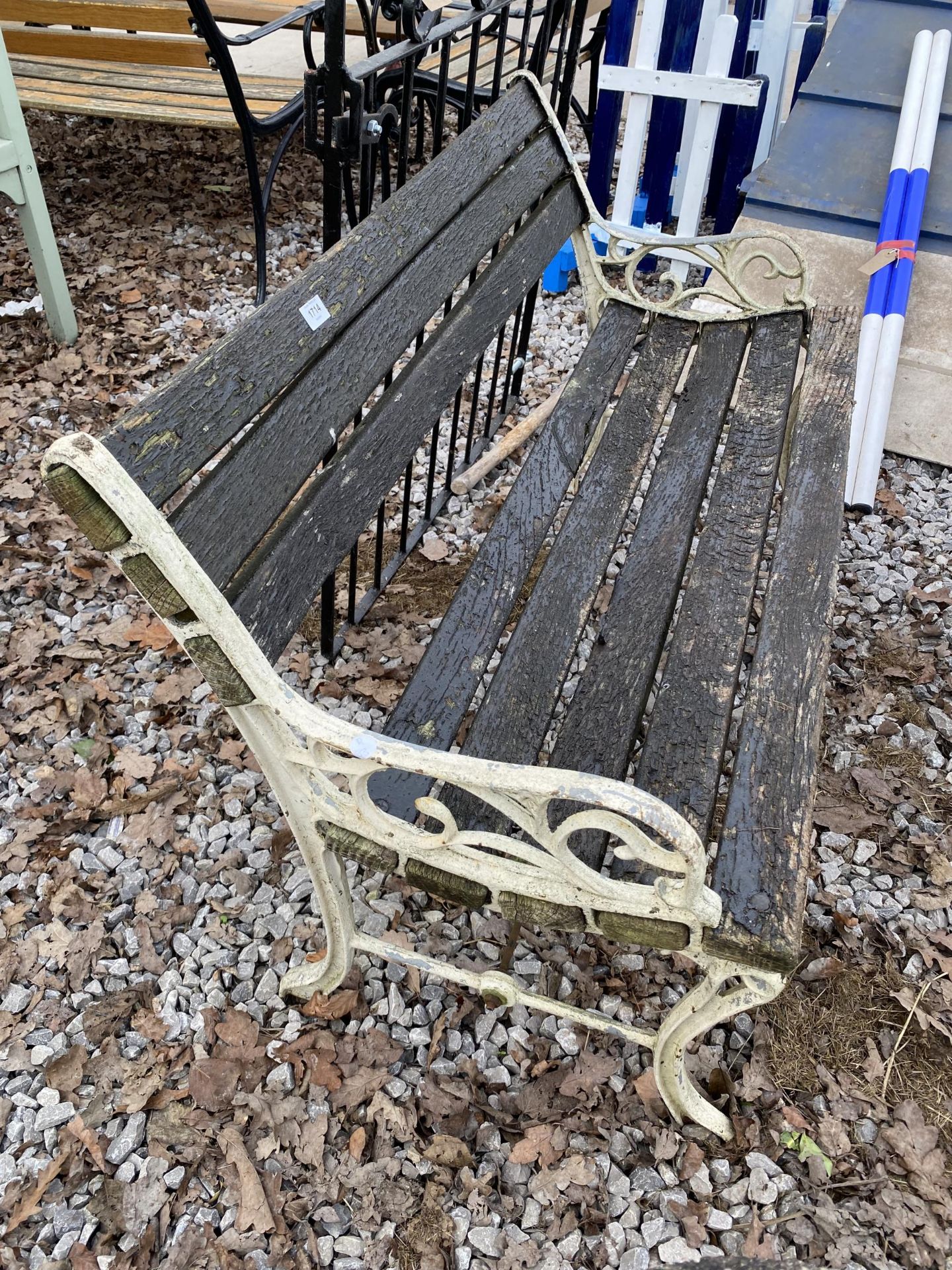 A WOODEN SLATTED GARDEN BENCH WITH CAST BENCH ENDS