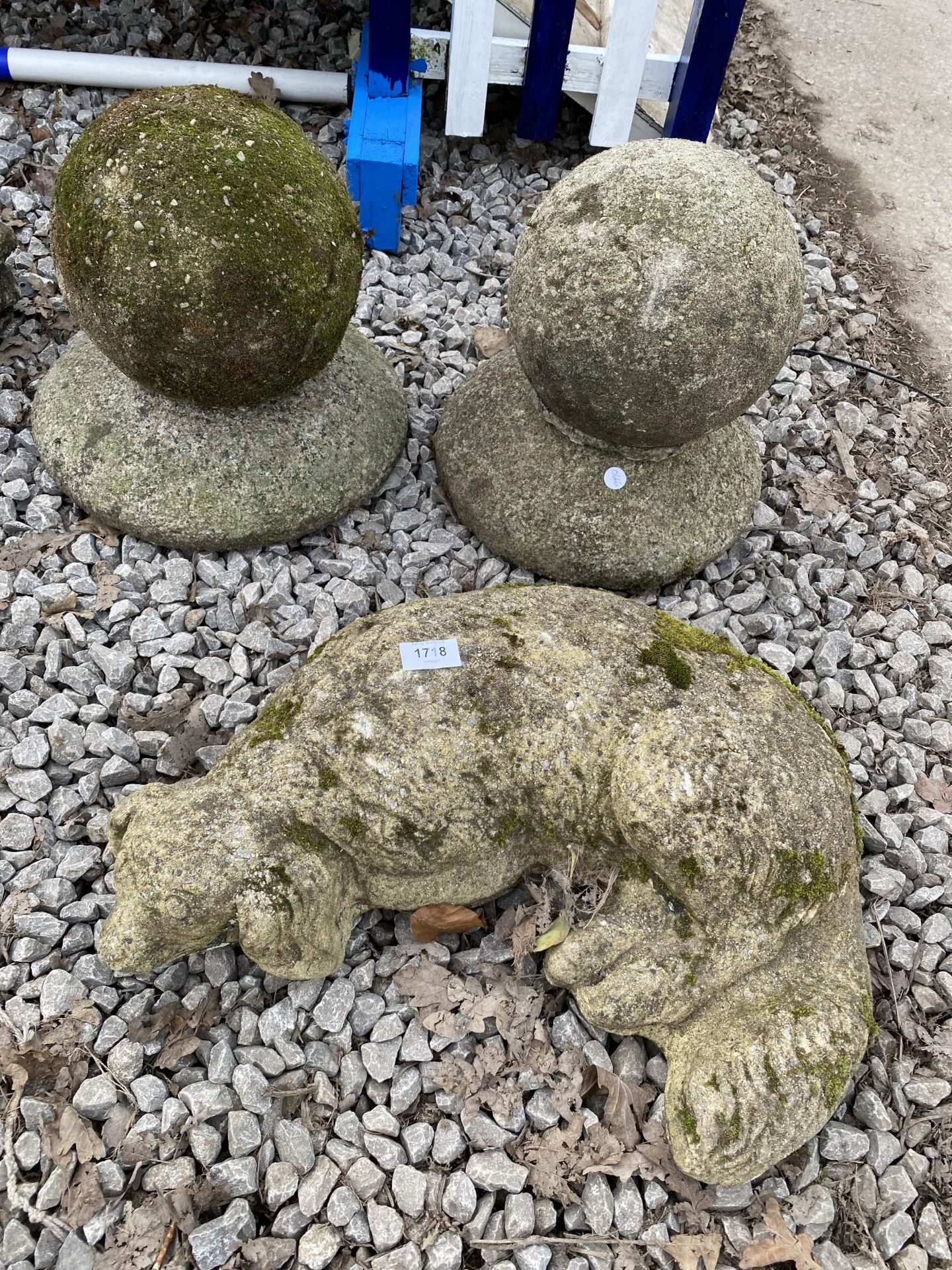 A RECONSTITUTED STONE DOG AND A PAIR OF POST FINIALS