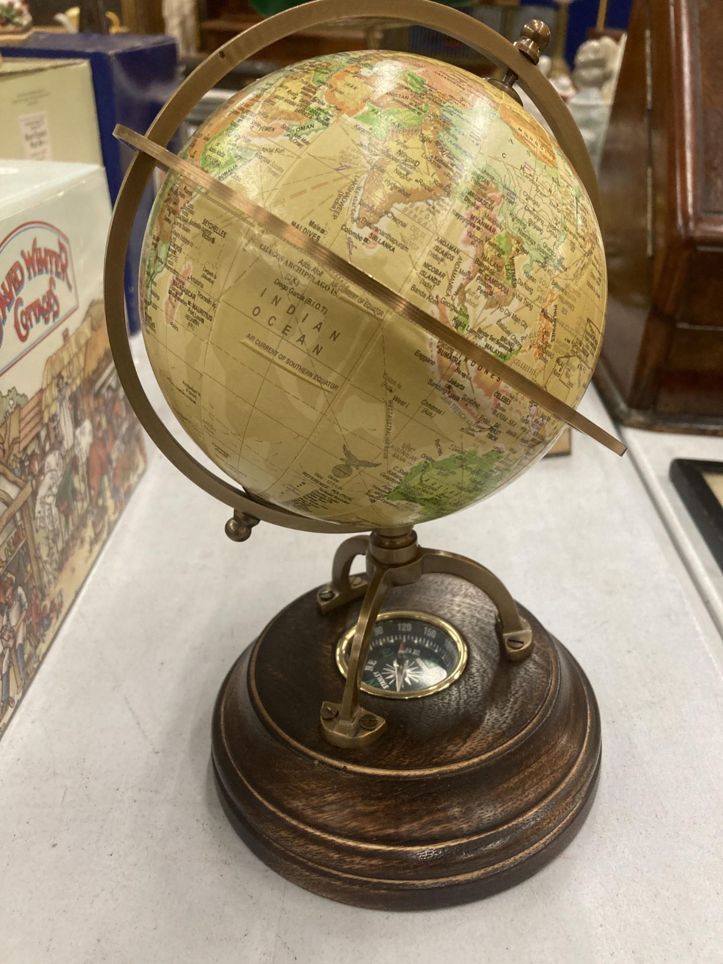 A WORLD GLOBE WITH A COMPASS ON A WOODEN BASE HEIGHT APPROX 24CM