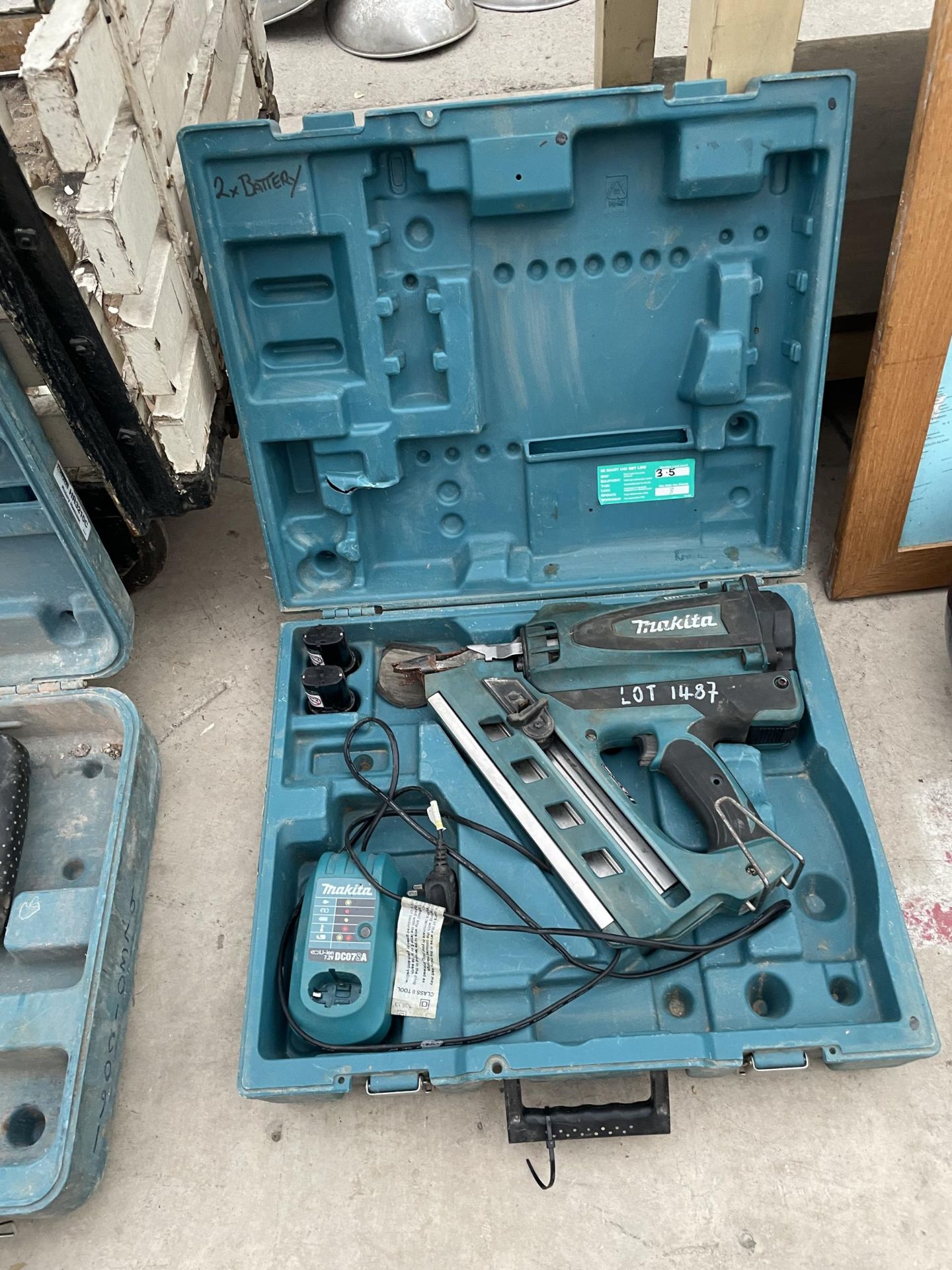A MAKITA BATTERY POWERED NAIL GUN WITH CHARGER AND TWO BATTERIES