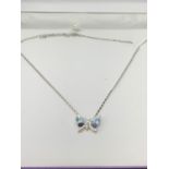 A SILVER NECKLACE WITH A BUTTERFLY AND BLUE STONE PENDANT IN A PRESENTATION BOX