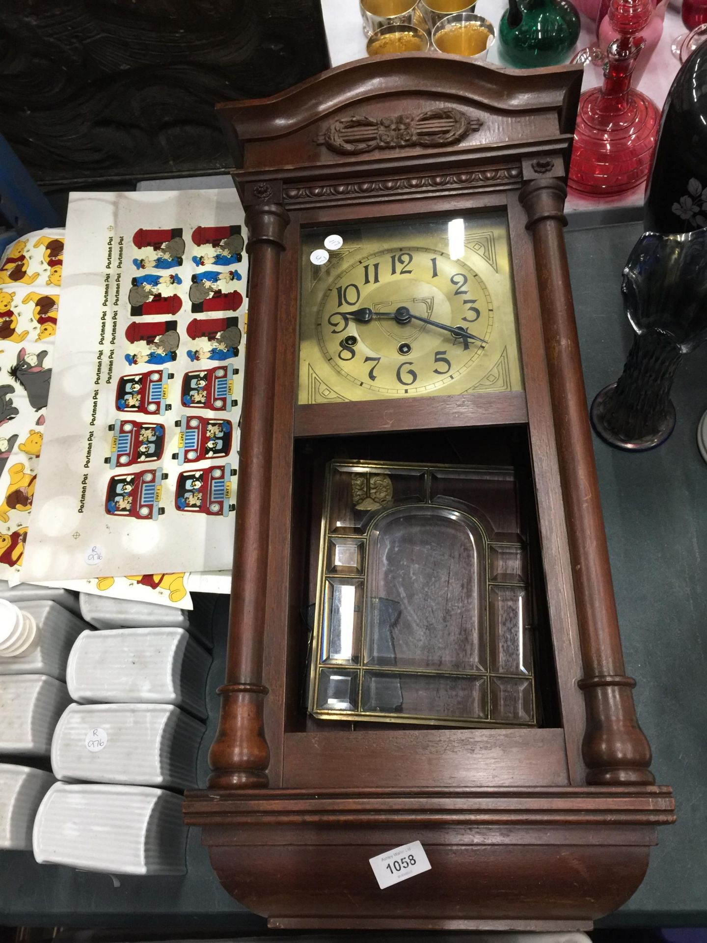 A MAHOGANY FRAMED WALL CLOCK WITH BEVELLED GLASS DOOR, PENDULUM AND KEY IN NEED OF SOME