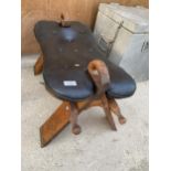 A WOODEN AND LEATHER TOPPED SADDLE STYLE STOOL