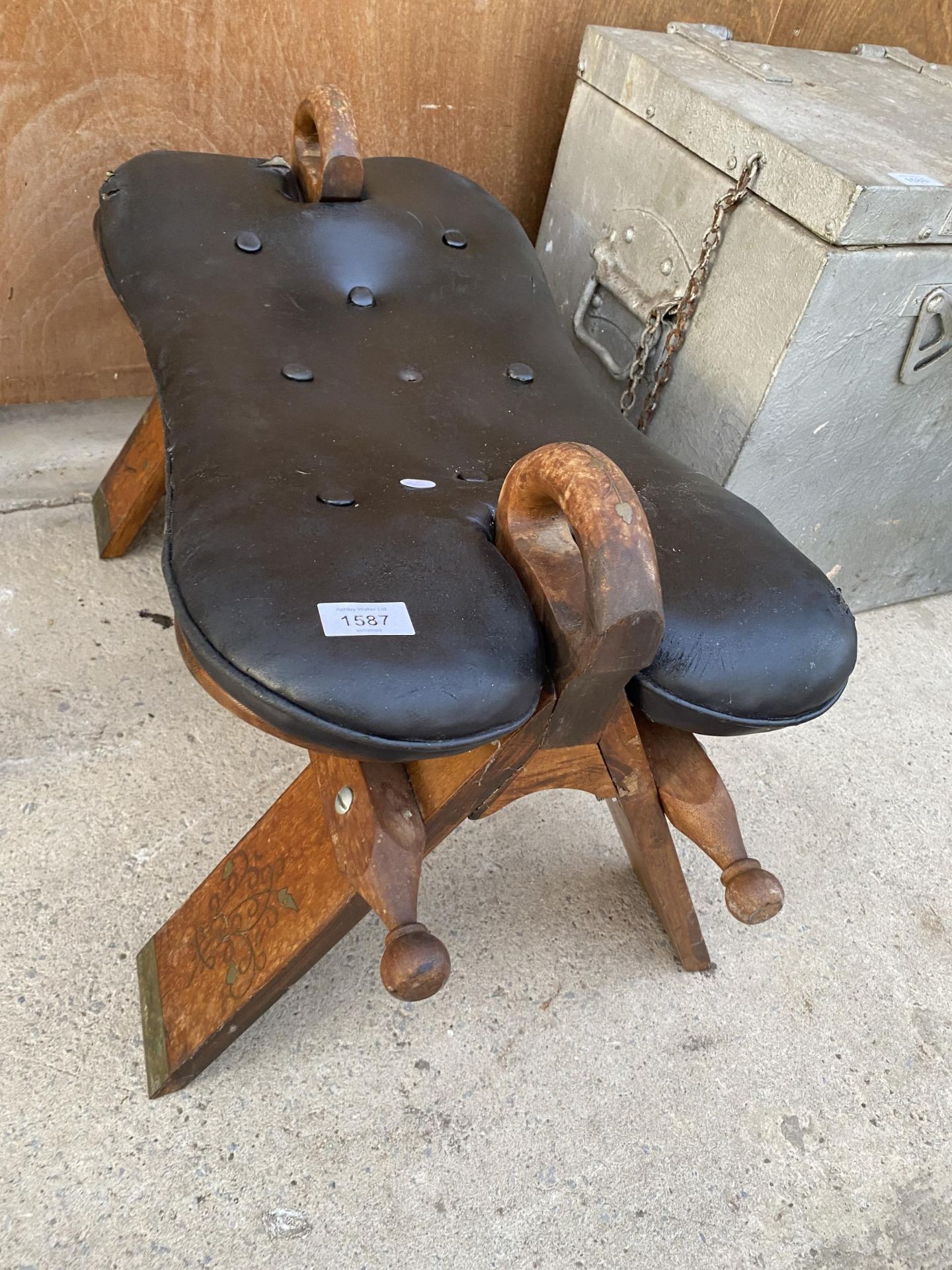 A WOODEN AND LEATHER TOPPED SADDLE STYLE STOOL