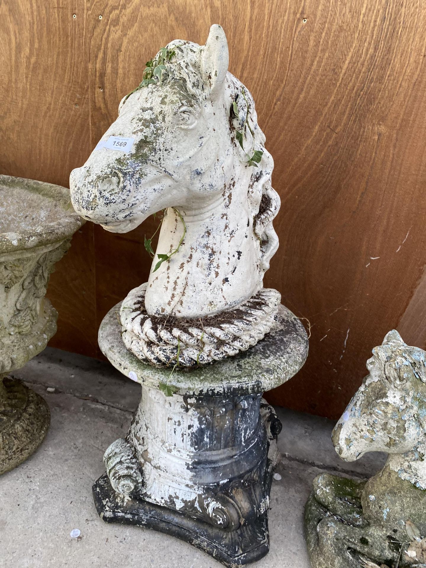 A RECONSTITUTED STONE HORSES HEAD WITH PEDESTAL BASE