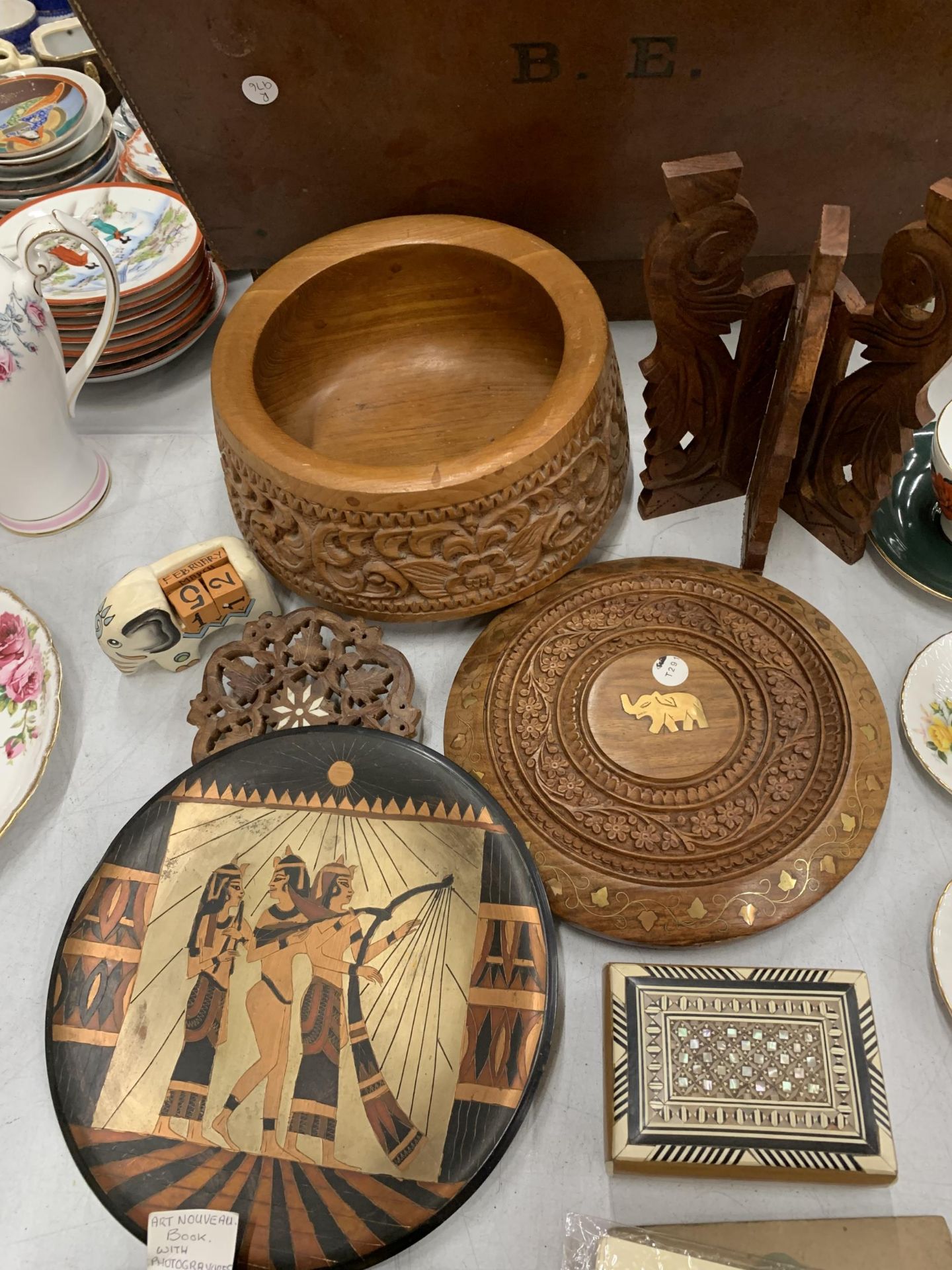 A QUANTITY OF TREEN ITEMS TO INCLUDE A HEAVILY CARVED BOWL, TRIVETS, AN ELEPHANT PERPETUAL CALENDAR,