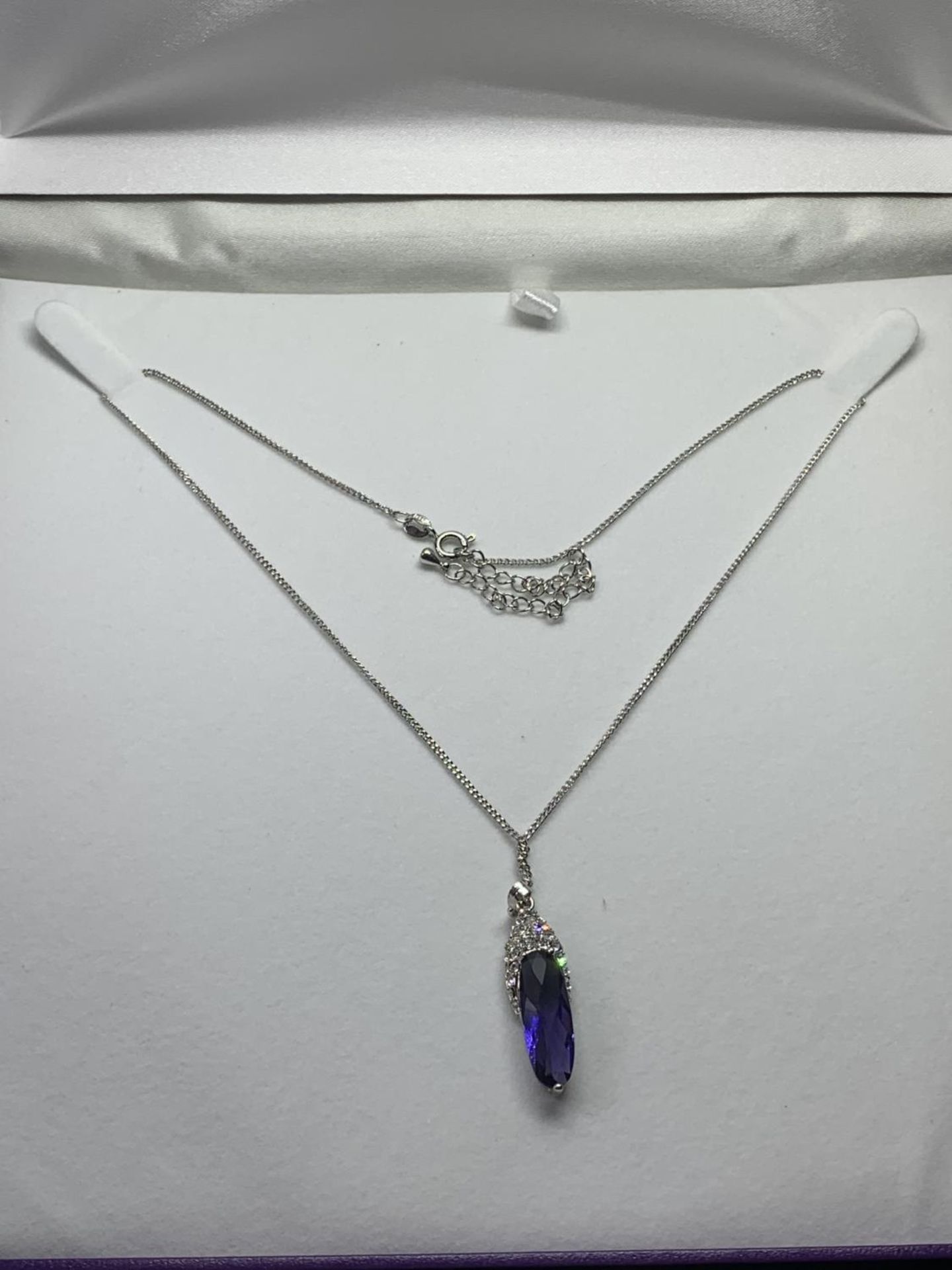 A SILVER NECKLACE WITH A PURPLE STONE PENDANT IN A PRESENTATION BOX