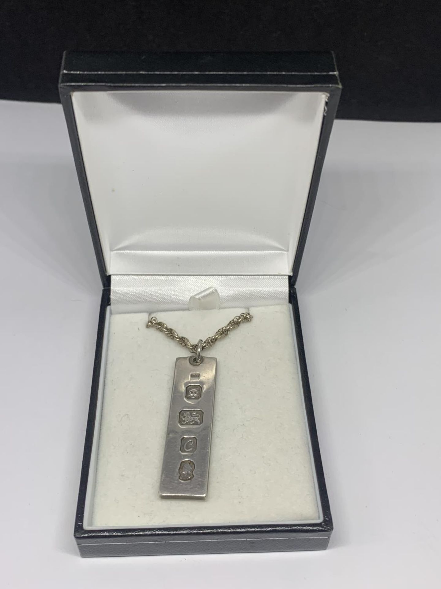 A SILVER INGOT ON A CHAIN IN A PRESENTATION BOX