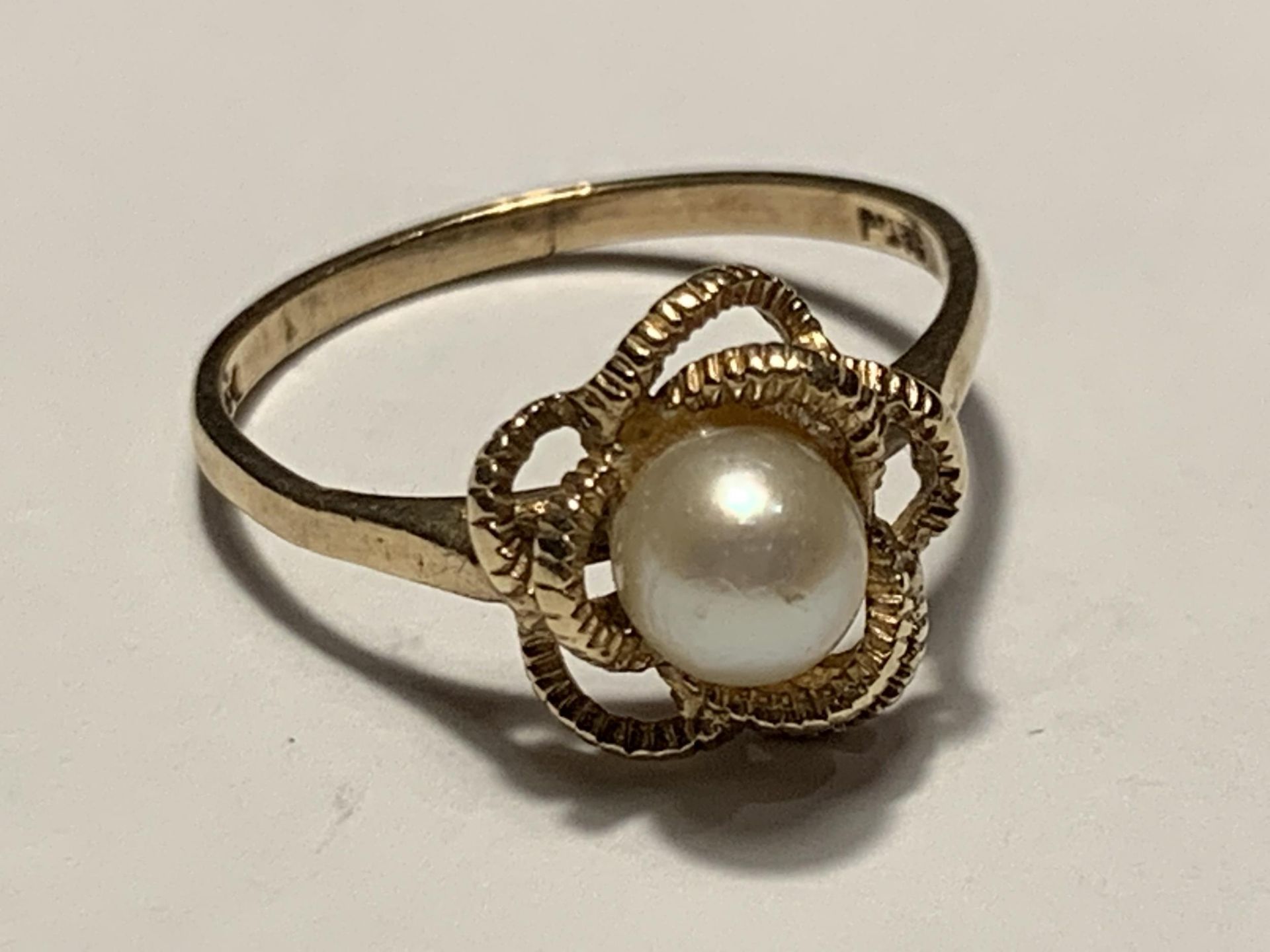A 9 CARAT GOLD RING WITH A CENTRE PEARL IN A TWIST DESIGN SIZE O/P