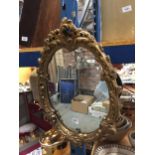 A VINTAGE STYLE OVAL MIRROR WITH ORNATE GILT FRAME