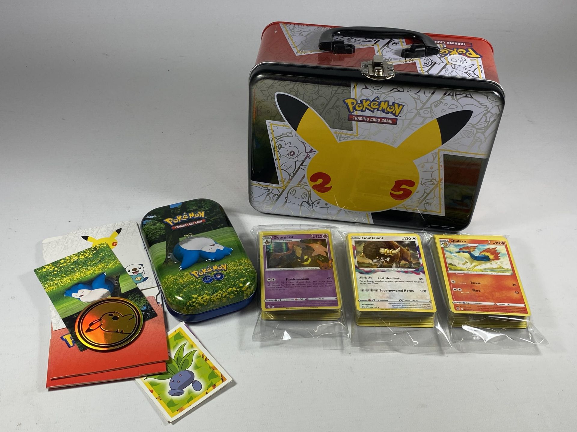 A POKEMON 25TH ANNIVERSARY TIN WITH ASSORTED CARDS, GAME TOKENS ETC