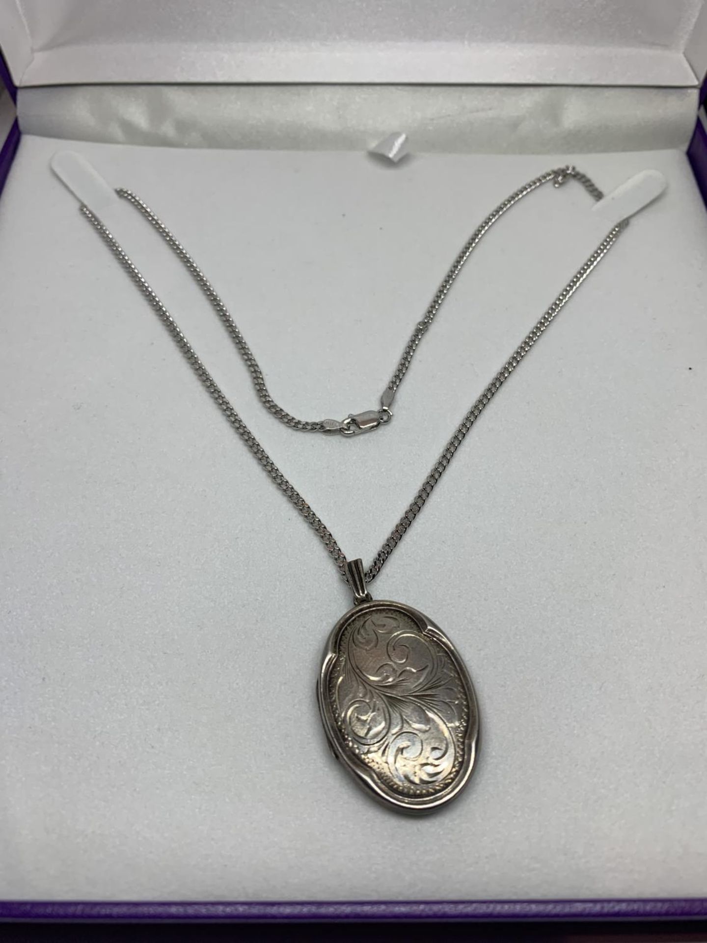 A SILVER NECKLACE WITH A SILVER LOCKET IN A PRESENTATION BOX