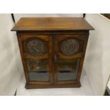 A VINTAGE OAK SMOKERS CABINET WITH CHERUB DESIGN CIRCULAR PLAQUES, INNER DRAWERS AND PULL OUT