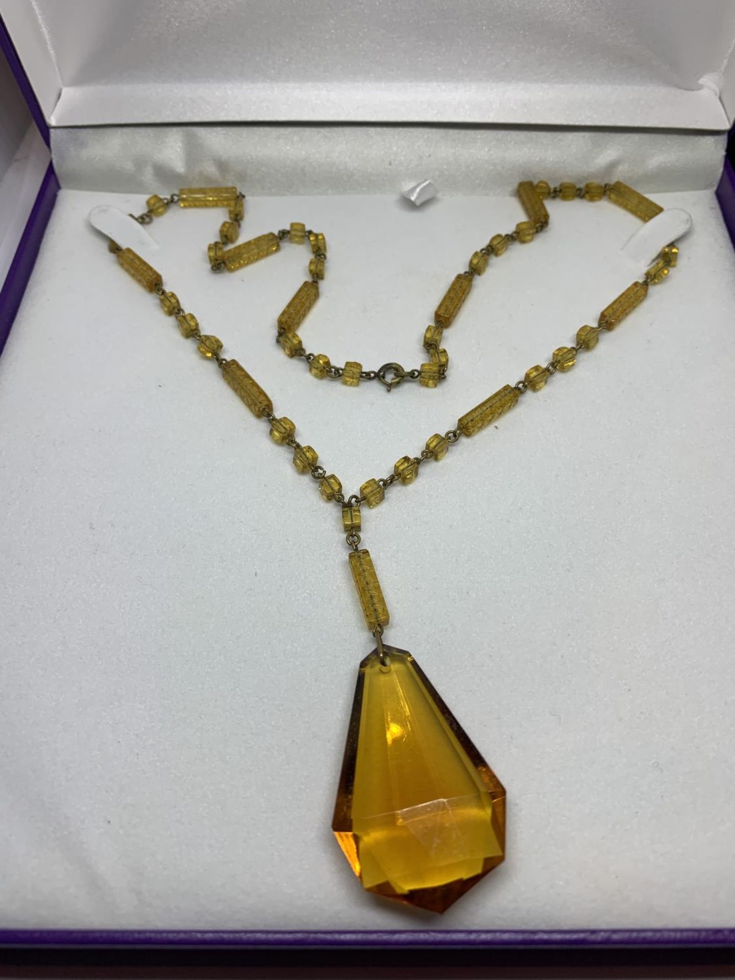 A YELLOW COLOURED NECKLACE IN A PRESENTATION BOX
