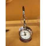 A CHROME POCKET WATCH STYLE CLOCK ON A CHROME STAND WITH WOODEN BASE