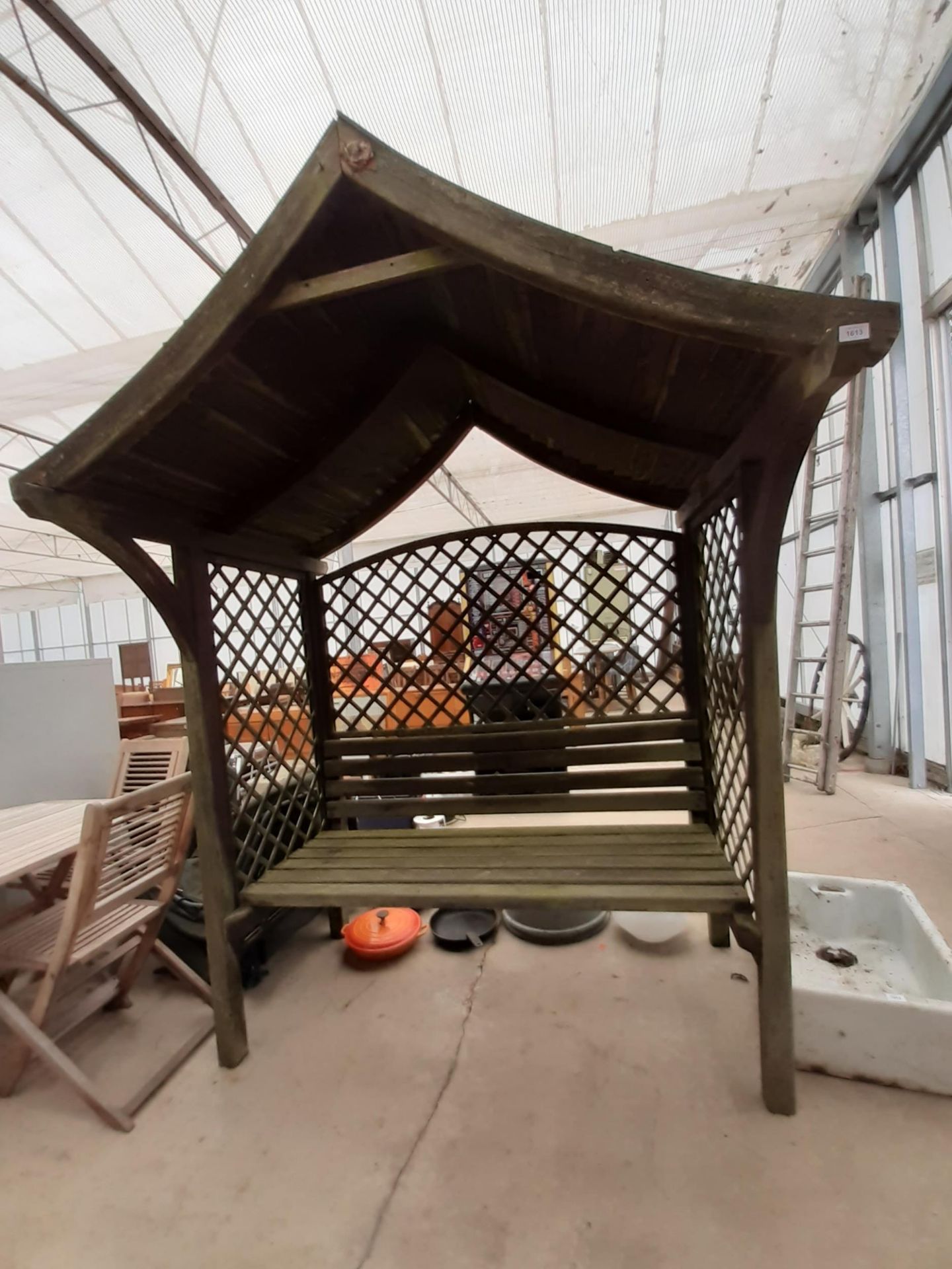 A WOODEN GARDEN BENCH SEAT WITH TRELIS SIDES AND BACK AND A WOODEN PITCHED ROOF (W:163CM)