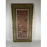 A GILT FRAMED CHINESE SILK PICTURE OF FIGURES ON A RED SILK GROUND, 67 X 34CM