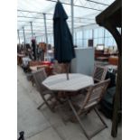 AN OCTAGONAL TEAK FOLDING PATIO TABLE COMPLETE WITH SIX CHAIRS AND A PARASOL