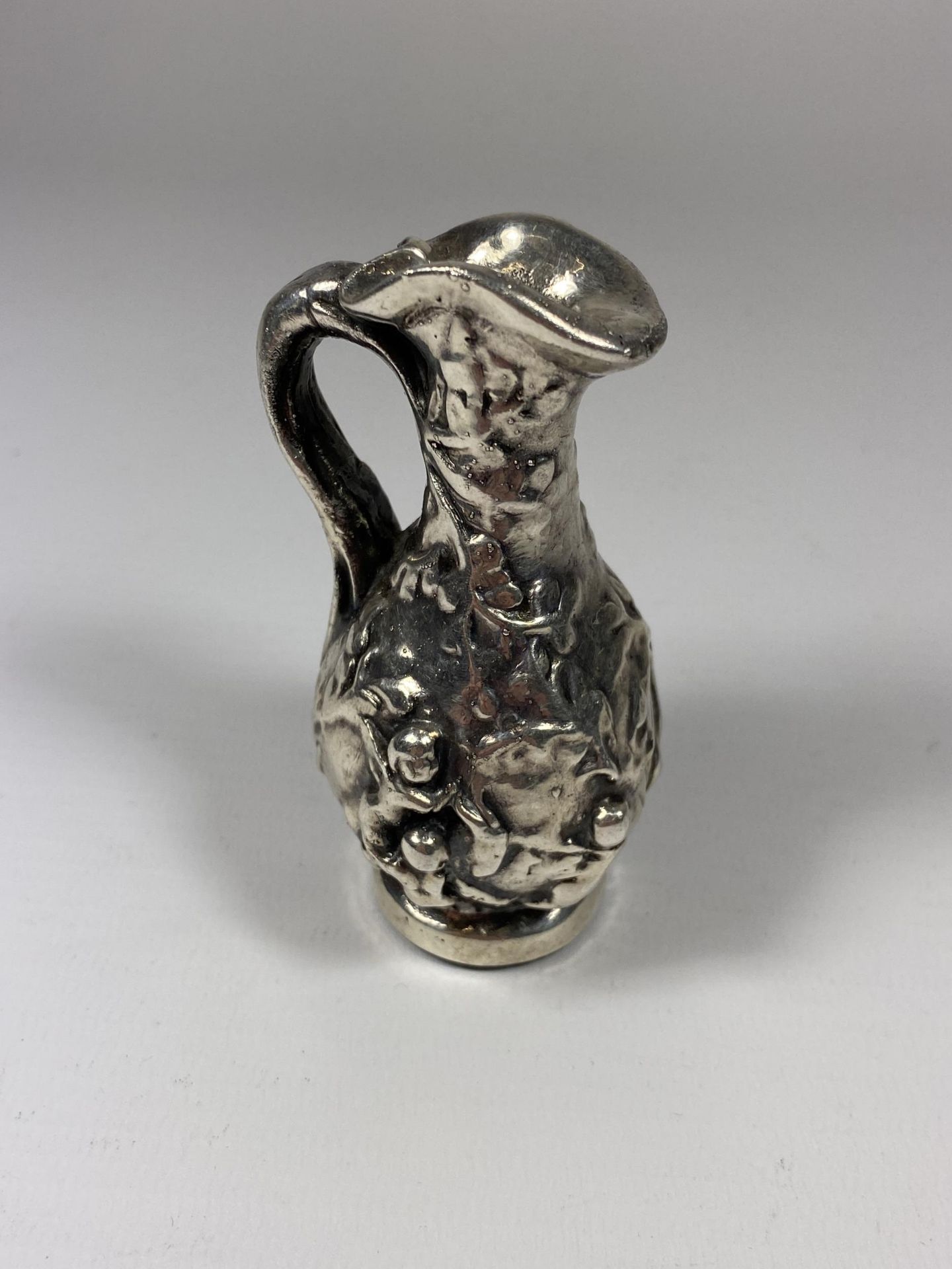 A SILVER GRECIAN DESIGN SMALL JUG