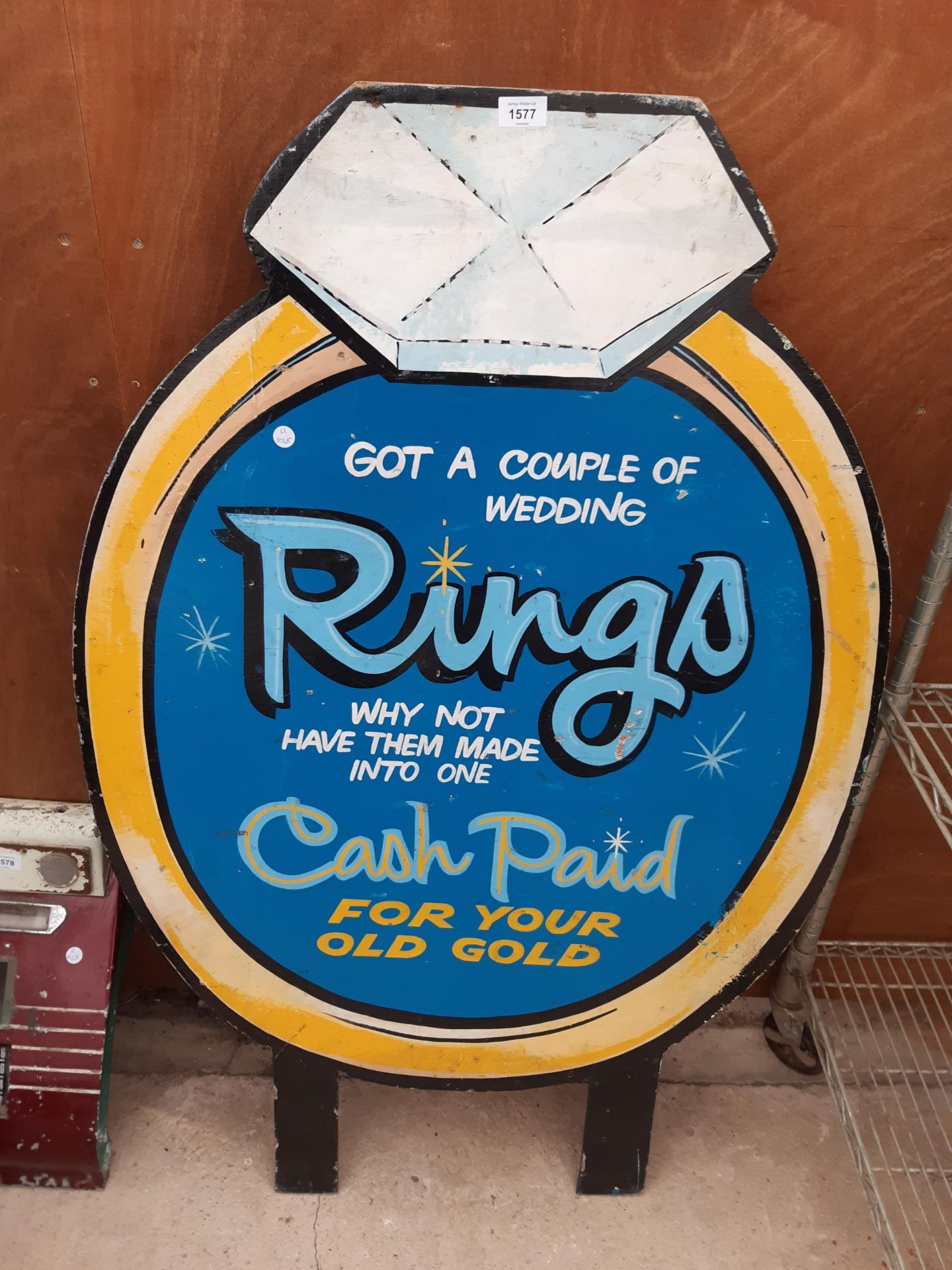 A WOODEN HAND PAINTED RING ADVERTISING SIGN