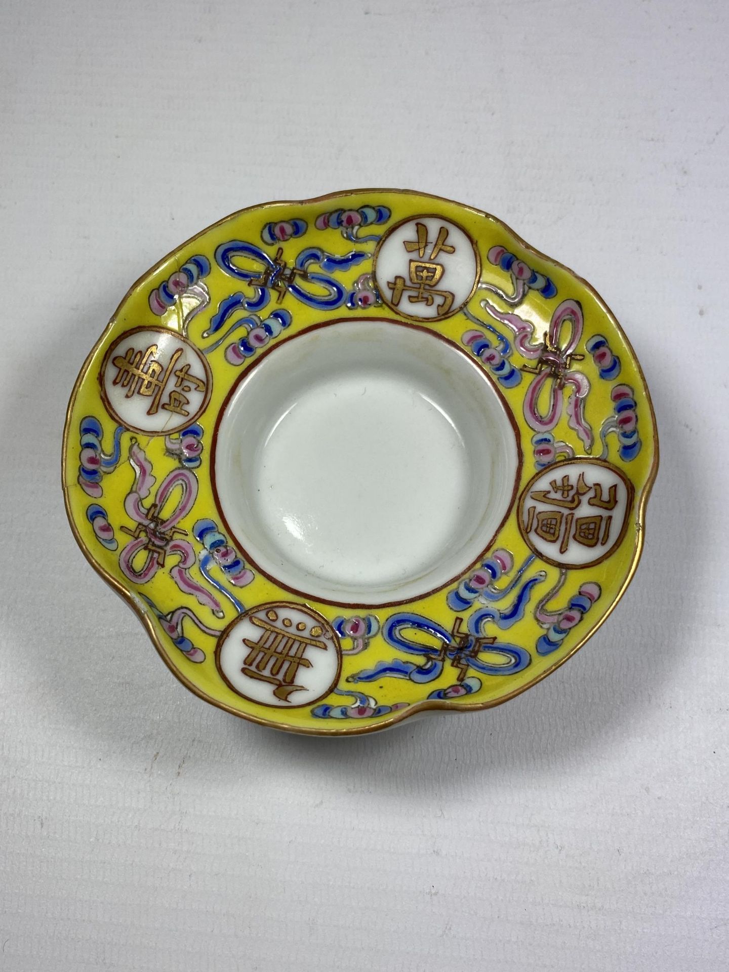 AN UNUSUAL CHINESE PORCELAIN FAMILLE JAUNE ARMORIAL TYPE DISH, DIAMETER 10.5CM (A/F)