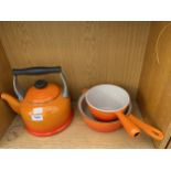 AN ORANGE LE CREUSET KETTLE AND TWO ORANGE LE CREUSET PANS