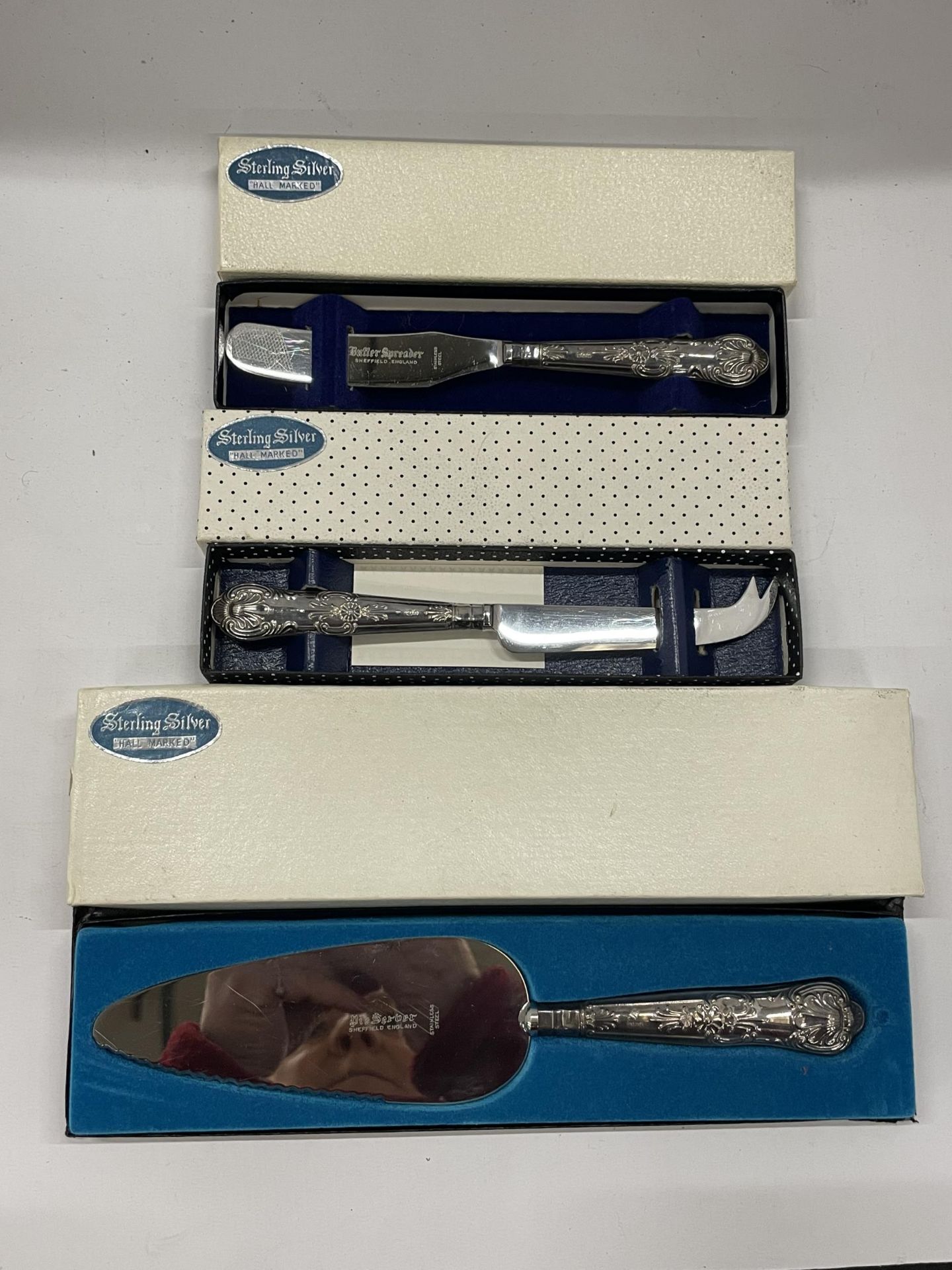 A GROUP OF THREE BOXED HALLMARKED SILVER HANDLED ITEMS TO INCLUDE A CAKE SLICE