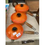 THREE GRADUATED WOODEN HANDLED CAST IRON LE CREUSET PANS