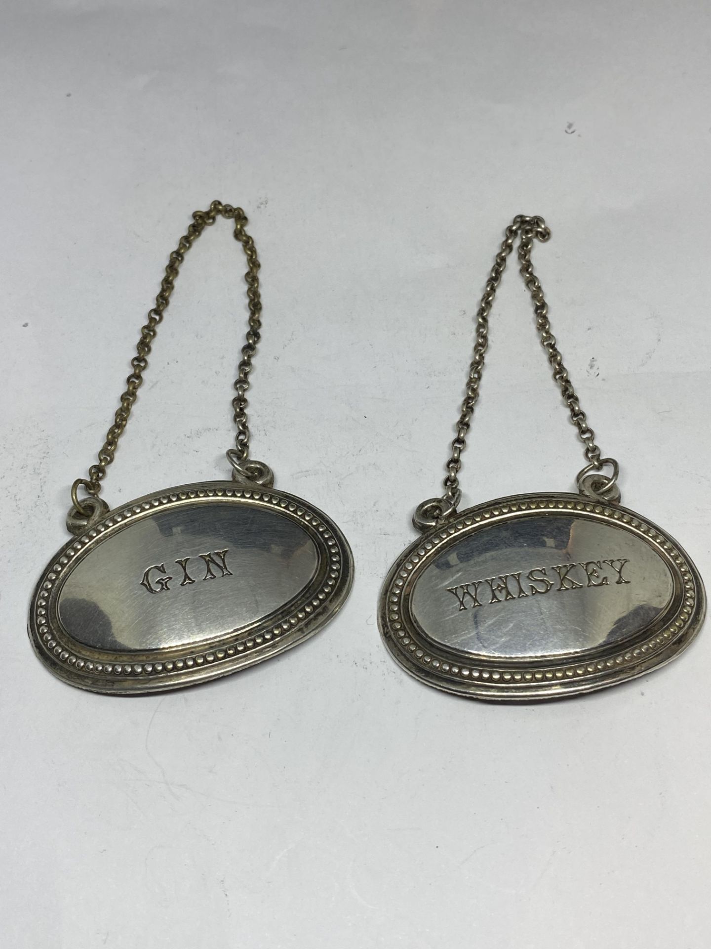 TWO WHITE METAL DECANTER LABELS - GIN AND WHISKEY