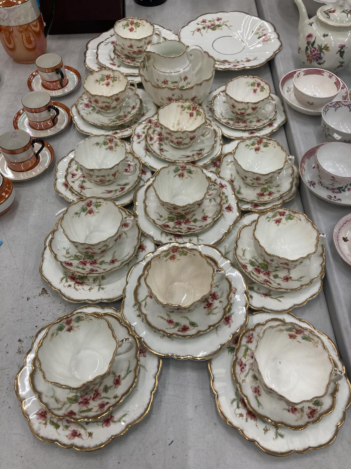 AN ANTIQUE DIAMOND CHINA TEASET TO INCLUDE A LARGE NUMBER OF TRIOS, TWO CAKE PLATES, A CREAM JUG AND