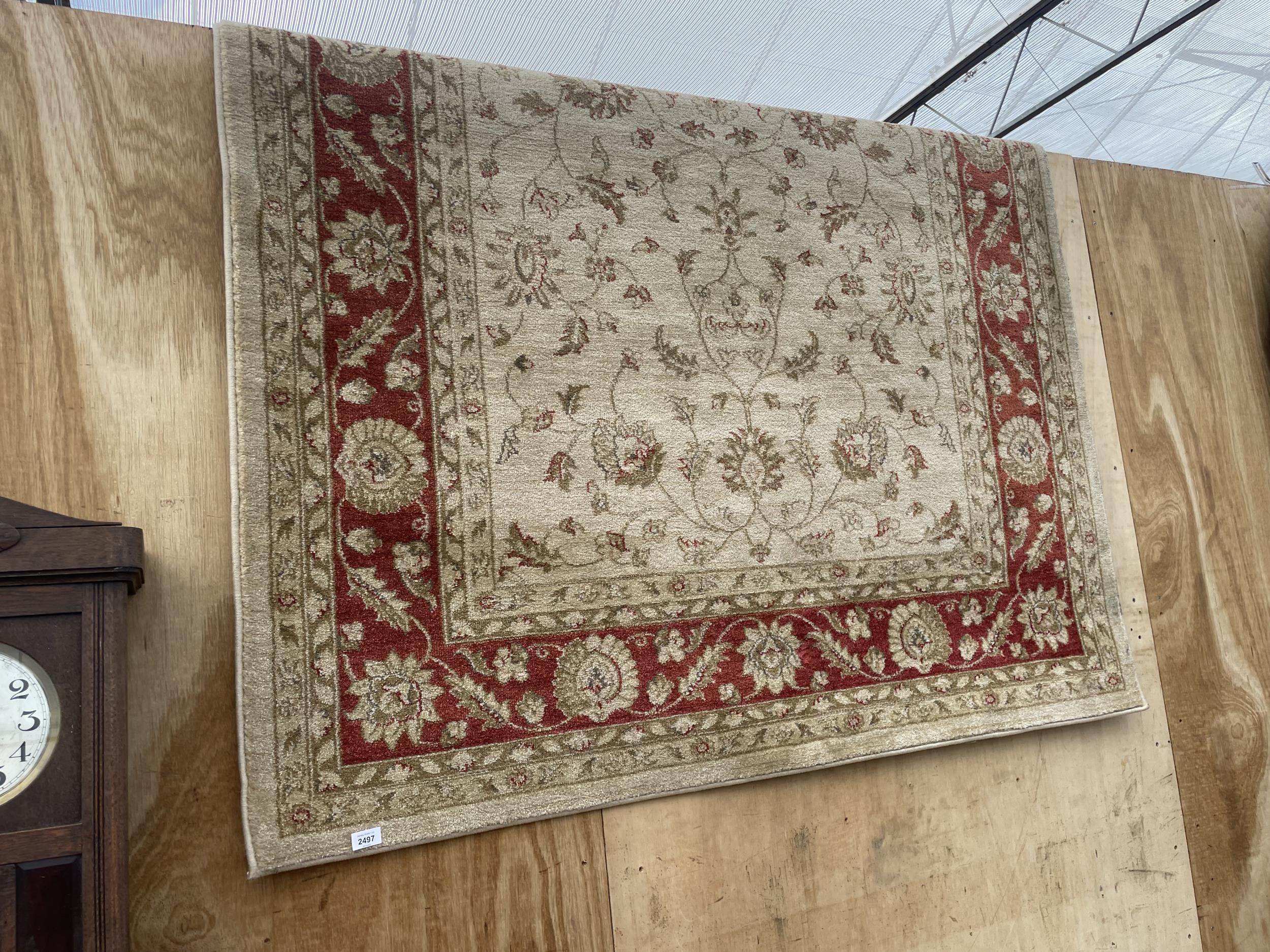 A LARGE RED AND CREAM PATTERNED RUG