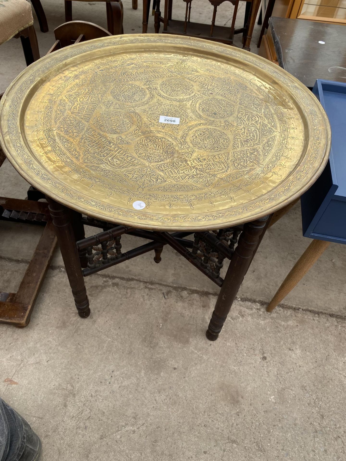 A MIDDLE EASTERN BRASS TABLE, 23.5" DIAMETER, ON FOLDING BASE