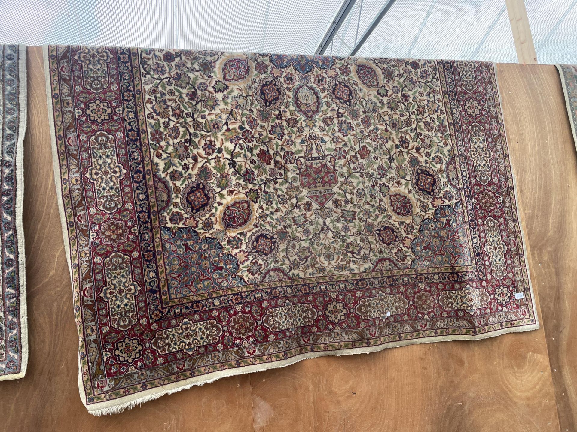 A LARGE RED PATTERNED FRINGED RUG