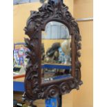 A CARVED OAK MIRROR WITH FOLIATE DECORATION